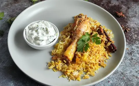 Pyszny kurczak biryani z ryżem, jogurtowym dipem i przyprawami.