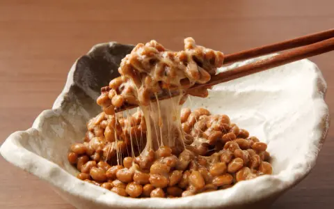 Natto co to? Sfermentowana soja z charakterystyczną, ciągnącą się konsystencją, podana w miseczce, nabierana pałeczkami.