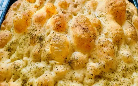 Chrupiąca pizza focaccia z ziołami, świeżo wyjęta z pieca. Idealna na przekąskę.