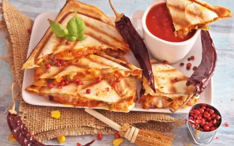 Pyszna quesadilla z serem i papryczkami chili, podana z sosem pomidorowym i ziarnami pieprzu.
