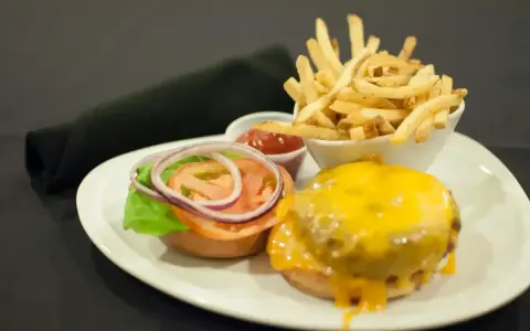 Talerz z hamburgerem, frytkami i ketchupem.