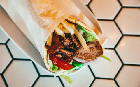 Pyszny kebab z mięsem, frytkami, warzywami i sosem. Zastanawiasz się, ile kcal ma kebab? Ten wygląda na sycący!