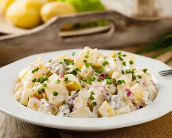 Pyszna, oryginalna kartoffelsalat z ziemniaków, ogórków kiszonych i cebuli, posypana szczypiorkiem.