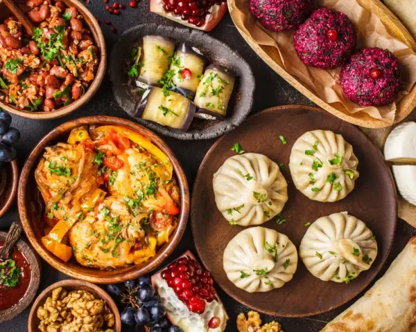 Bogactwo smaków Gruzji: khinkali, fasola, bakłażany, ser i mięso w sosie. Pyszne dania gruzińskie na stole.