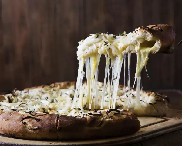 Rozpływający się ser z pizzy quattro formaggi ciągnie się w długich nitkach. Pyszny, gorący przysmak.