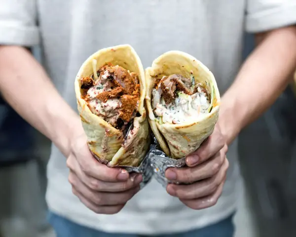 Dwie porcje pysznego, soczystego kebab na cienkim, zawinięte w tortillę, z sosem i warzywami.