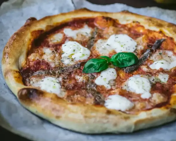 Pyszna pizza z anchois, mozzarellą i bazylią. Jeden z wielu pysznych rodzajów pizzy, idealna na każdą okazję.