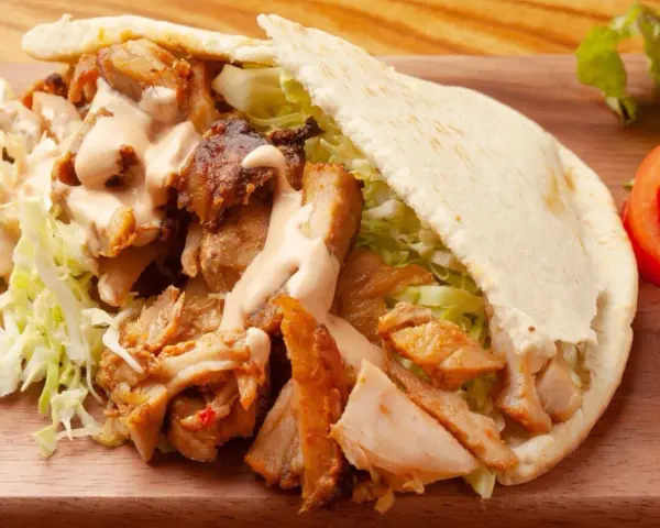 Pyszna bułka kebab z soczystym mięsem, chrupiącą sałatą i kremowym sosem. Idealna na szybki lunch.