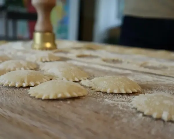 Ravioli co to? Świeżo przygotowane pierożki z ciasta makaronowego, posypane mąką, czekają na gotowanie.