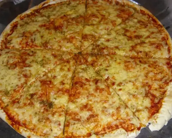 Pyszna pizza margerita z ciągnącym się serem i aromatycznymi ziołami, pokrojona na 8 kawałków.