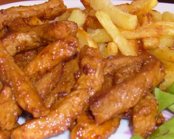 Pyszny gyros wieprzowy w sosie, podany z chrupiącymi frytkami i świeżą sałatą. Idealny posiłek dla każdego miłośnika mięsa.