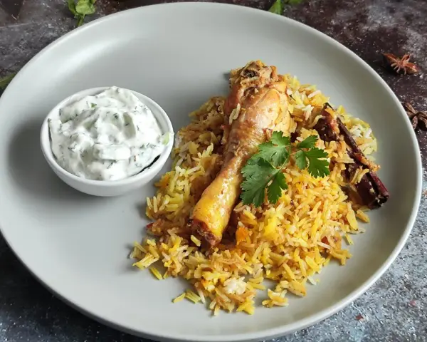 Pyszny kurczak biryani z ryżem, jogurtowym dipem i przyprawami.