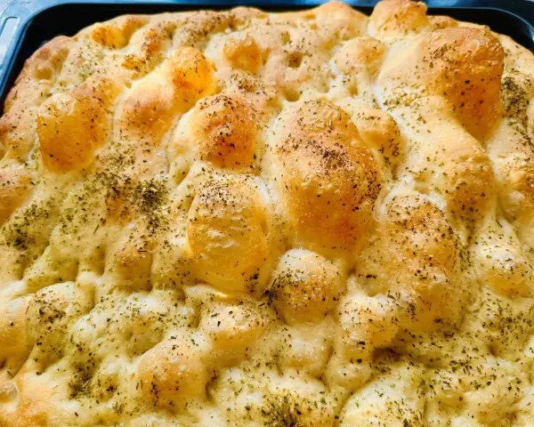 Chrupiąca pizza focaccia z ziołami, świeżo wyjęta z pieca. Idealna na przekąskę.