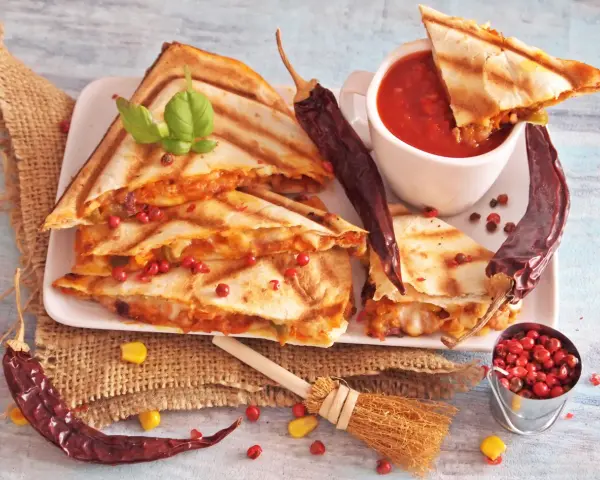 Pyszna quesadilla z serem i papryczkami chili, podana z sosem pomidorowym i ziarnami pieprzu.