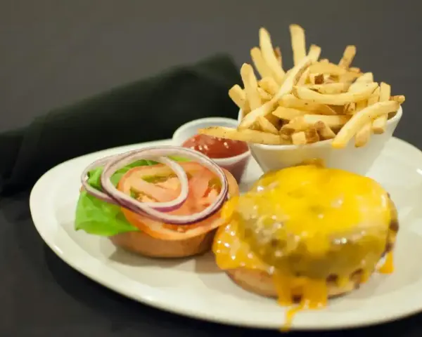 Talerz z hamburgerem, frytkami i ketchupem.