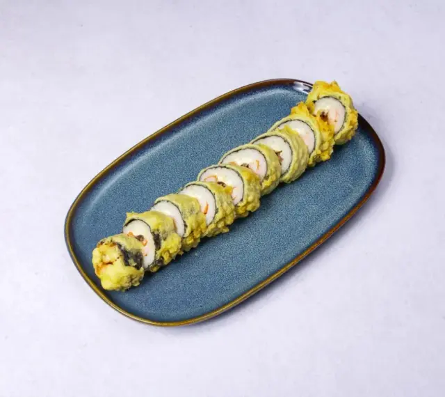 Chrupiące rolki sushi z rybą w tempurze, ułożone na niebieskim talerzu.