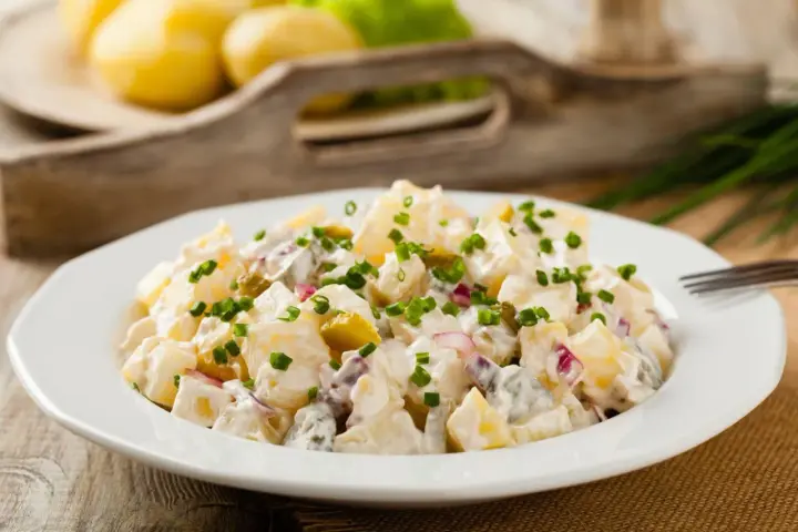 Pyszna, oryginalna kartoffelsalat z ziemniaków, ogórków kiszonych i cebuli, posypana szczypiorkiem.