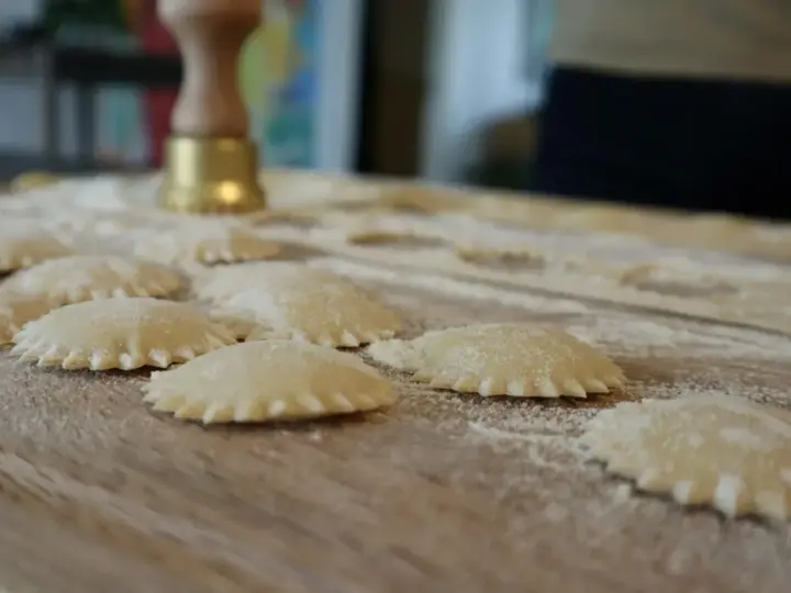 Ravioli co to? Świeżo przygotowane pierożki z ciasta makaronowego, posypane mąką, czekają na gotowanie.