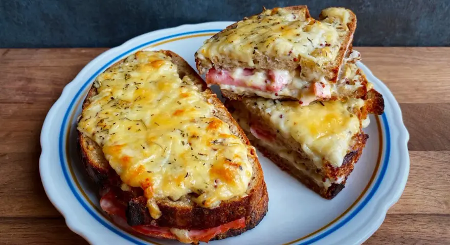 Dwa pyszne croque monsieur z rozpływającym się serem i szynką, posypane ziołami.