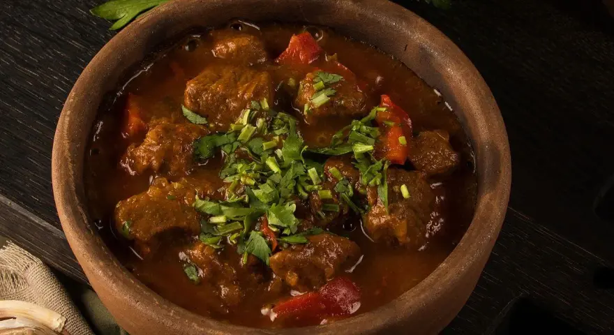 Gulasz z wołowiny w glinianej misie, posypany świeżą pietruszką. Aromatyczne czaszuszuli zachęcają do spróbowania.