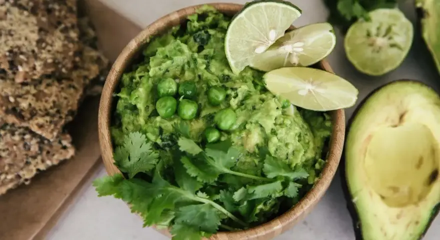 Pyszne guacamole co to? Kremowy dip z awokado, groszkiem, kolendrą i limonką, podany z chrupkimi krakersami.