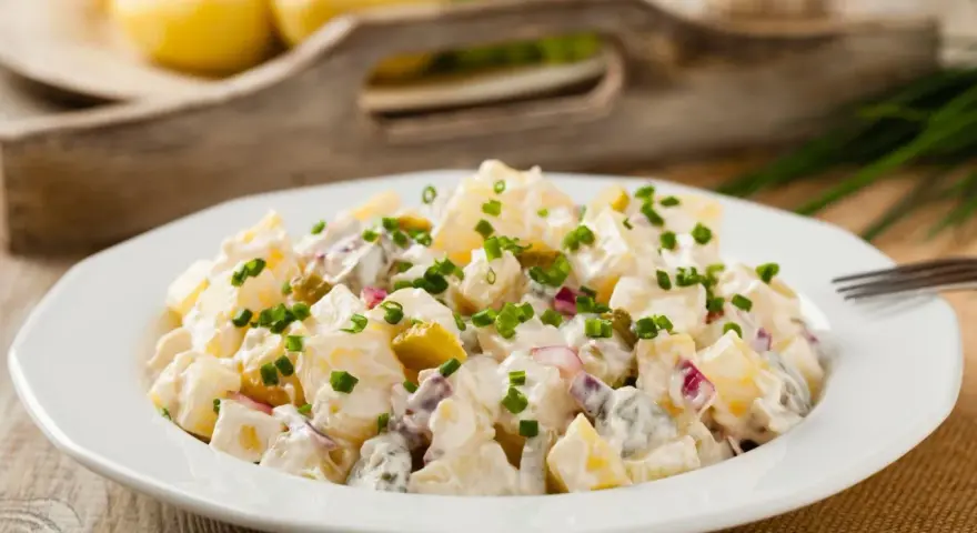 Pyszna, oryginalna kartoffelsalat z ziemniaków, ogórków kiszonych i cebuli, posypana szczypiorkiem.