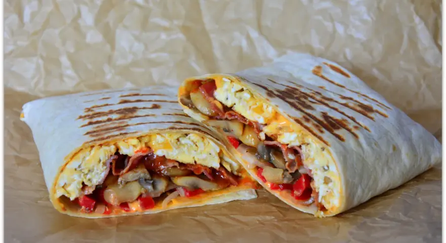 Pyszny wrap jajeczny z boczkiem, pieczarkami i papryką, idealny na śniadanie.