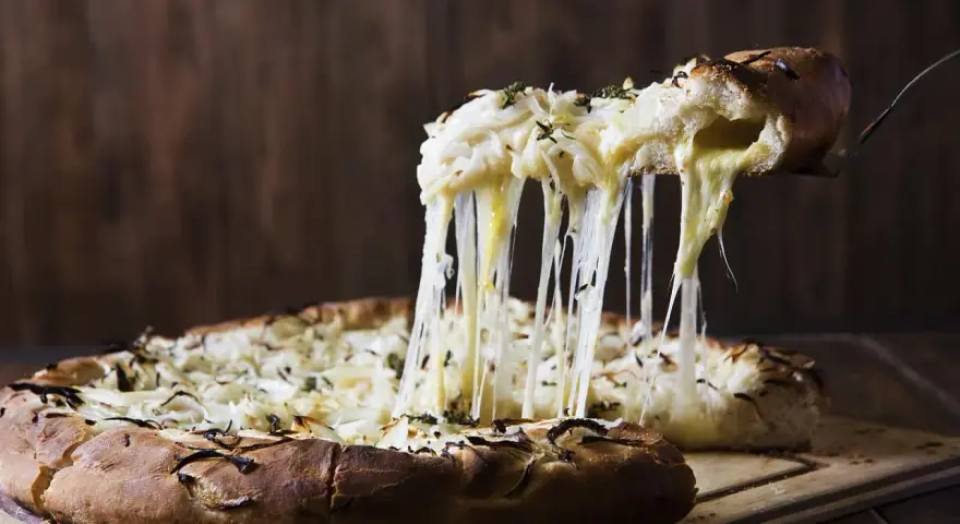 Rozpływający się ser z pizzy quattro formaggi ciągnie się w długich nitkach. Pyszny, gorący przysmak.