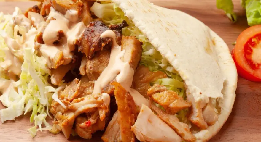 Pyszna bułka kebab z soczystym mięsem, chrupiącą sałatą i kremowym sosem. Idealna na szybki lunch.