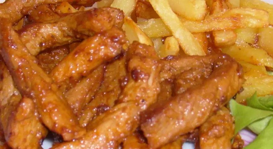 Pyszny gyros wieprzowy w sosie, podany z chrupiącymi frytkami i świeżą sałatą. Idealny posiłek dla każdego miłośnika mięsa.