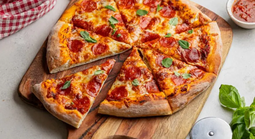 Apetyczna pizza pepperoni z ciągnącym się serem i świeżą bazylią, gotowa do podania.