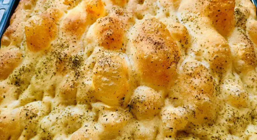 Chrupiąca pizza focaccia z ziołami, świeżo wyjęta z pieca. Idealna na przekąskę.
