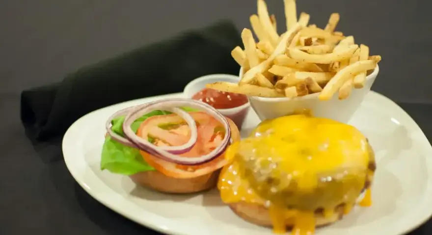 Talerz z hamburgerem, frytkami i ketchupem.