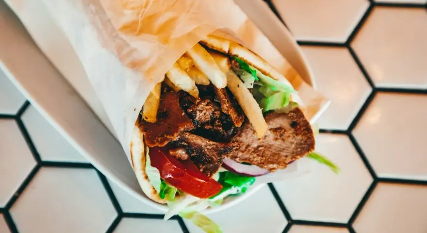 Pyszny kebab z mięsem, frytkami, warzywami i sosem. Zastanawiasz się, ile kcal ma kebab? Ten wygląda na sycący!