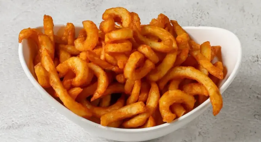 Miseczka pełna kręconych frytek creole, posypanych przyprawami.