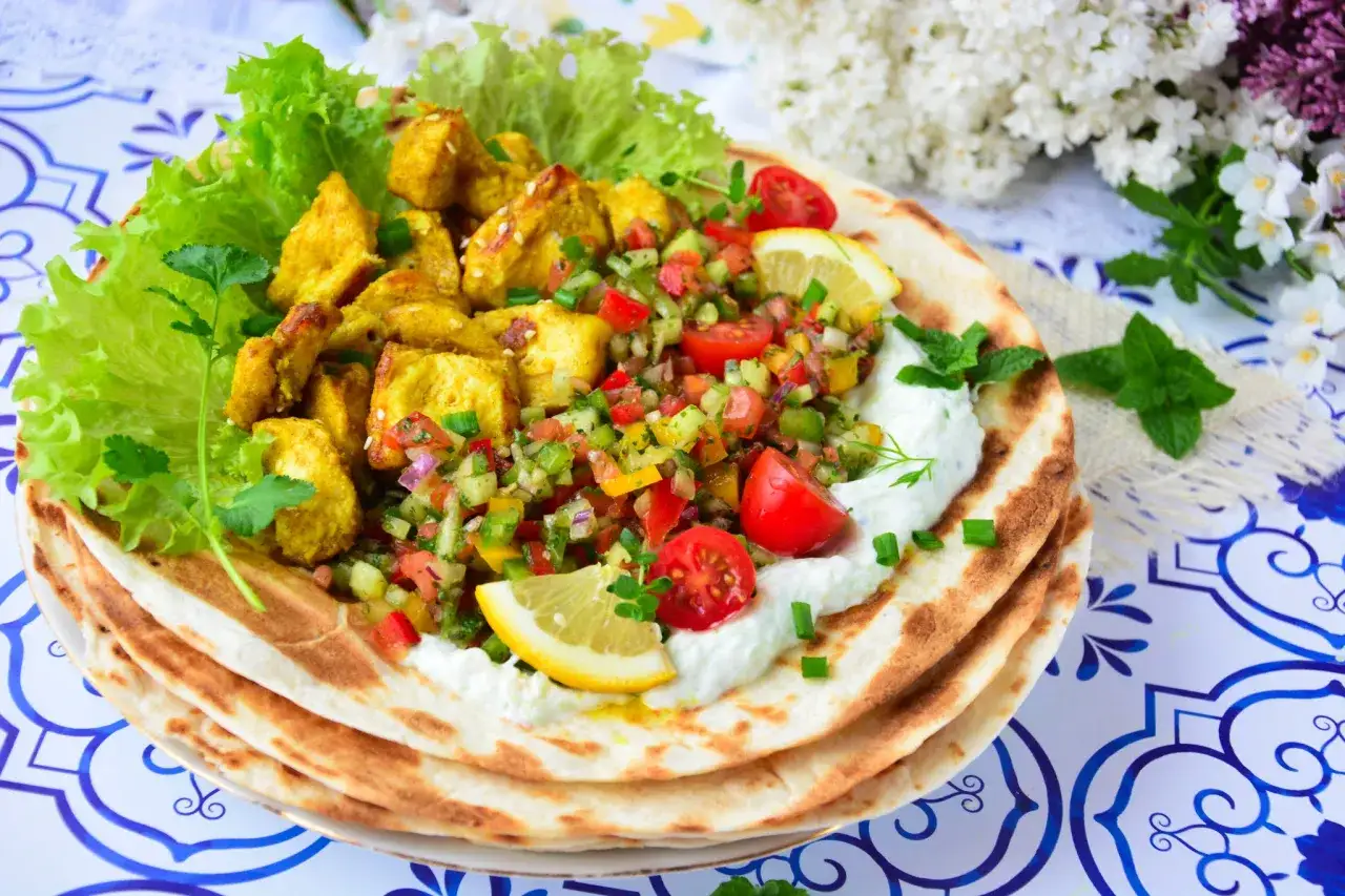 Pyszna shoarma z kurczaka na chlebku pita z jogurtowym sosem, świeżymi warzywami i cytryną.