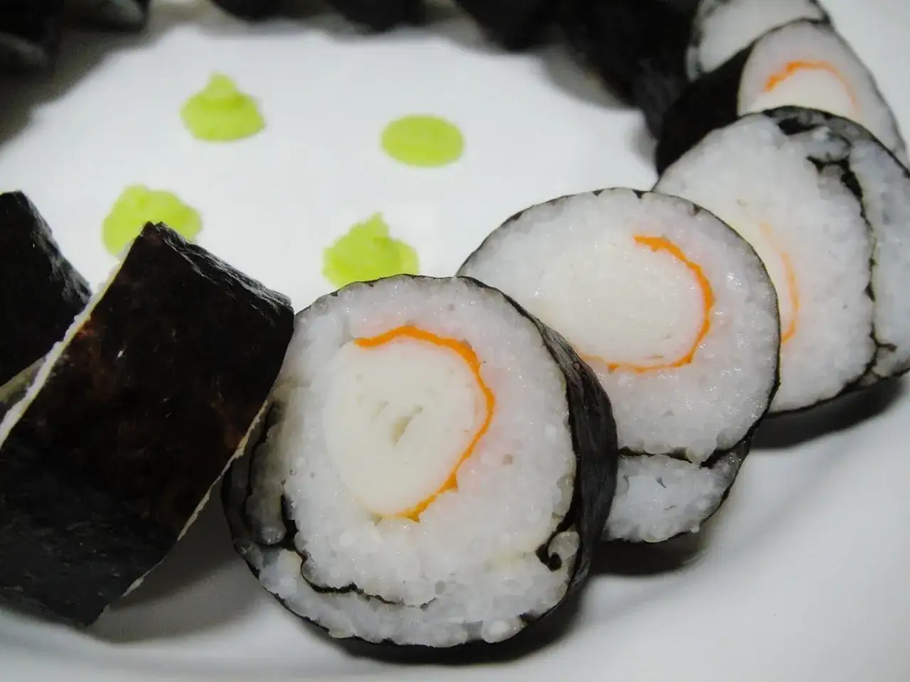 Roladki hosomaki z surimi, ryżem i nori, podane z zielonym wasabi.