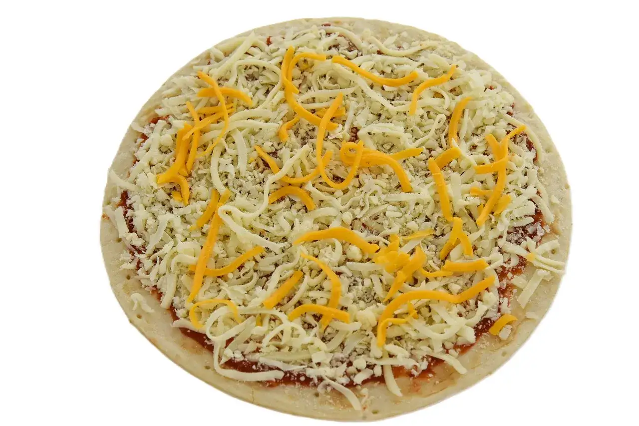 Pizza quattro formaggi gotowa do pieczenia, obficie posypana startymi serami.