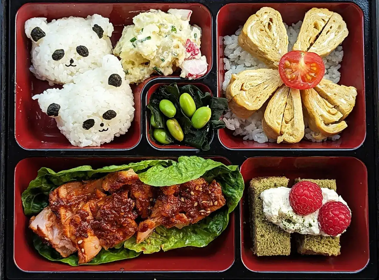 Uroczy bento co to? Dwa ryżowe misie, sałatka ziemniaczana, edamame, omlet w kształcie kwiatka, łosoś w sosie i deser z malinami.