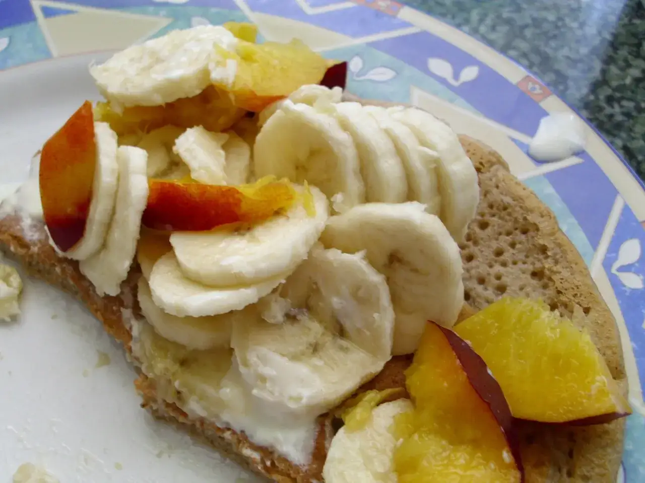 Plasterki banana i brzoskwini na naleśniku z kremem. Pyszne naleśniki na śniadanie.