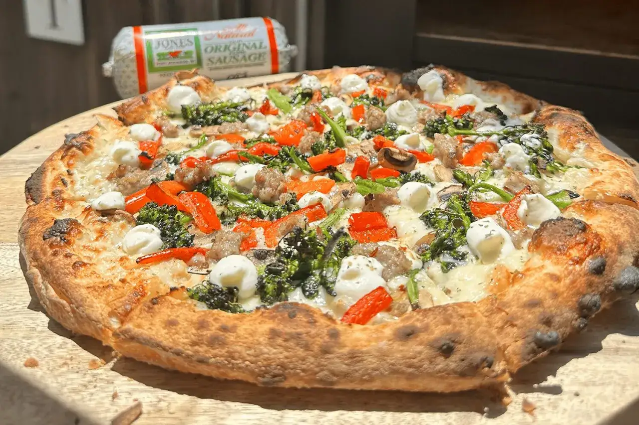 Pyszna pizza z kawałkami salsiccia, brokułami, papryką i mozzarellą na chrupiącym cieście.