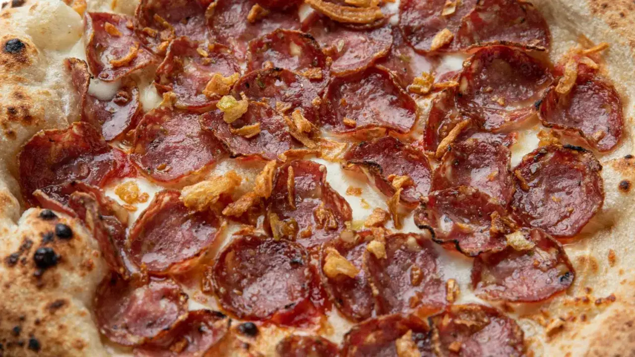 Pizza z chrupiącym ciastem, obficie pokryta plastrami pikantnego peperoni, roztopionym serem i chrupiącą cebulką.
