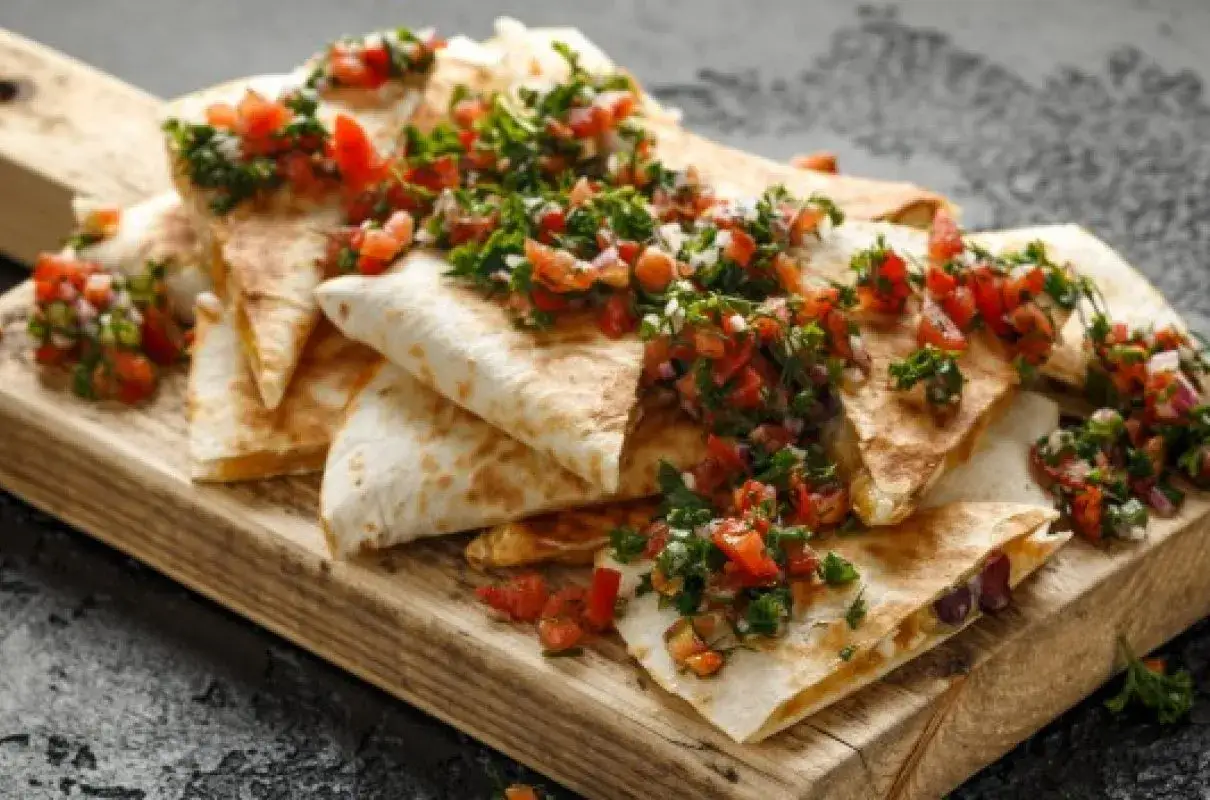 Chrupiące quesadillas z salsą pomidorową i kolendrą, idealne meksykańskie jedzenie na desce.