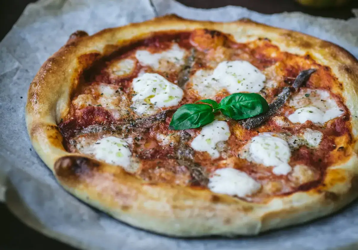 Pyszna pizza z mozzarellą, anchois i bazylią. To klasyczny przykład, co to jest pizza – danie, które zachwyca smakiem i aromatem.