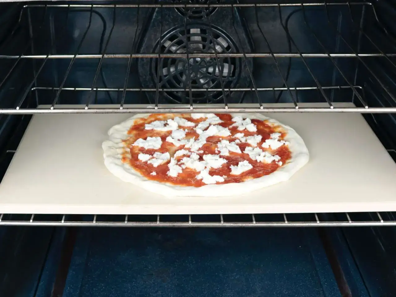 Pizza na kamieniu w piekarniku z termoobiegiem, gotowa do pieczenia.