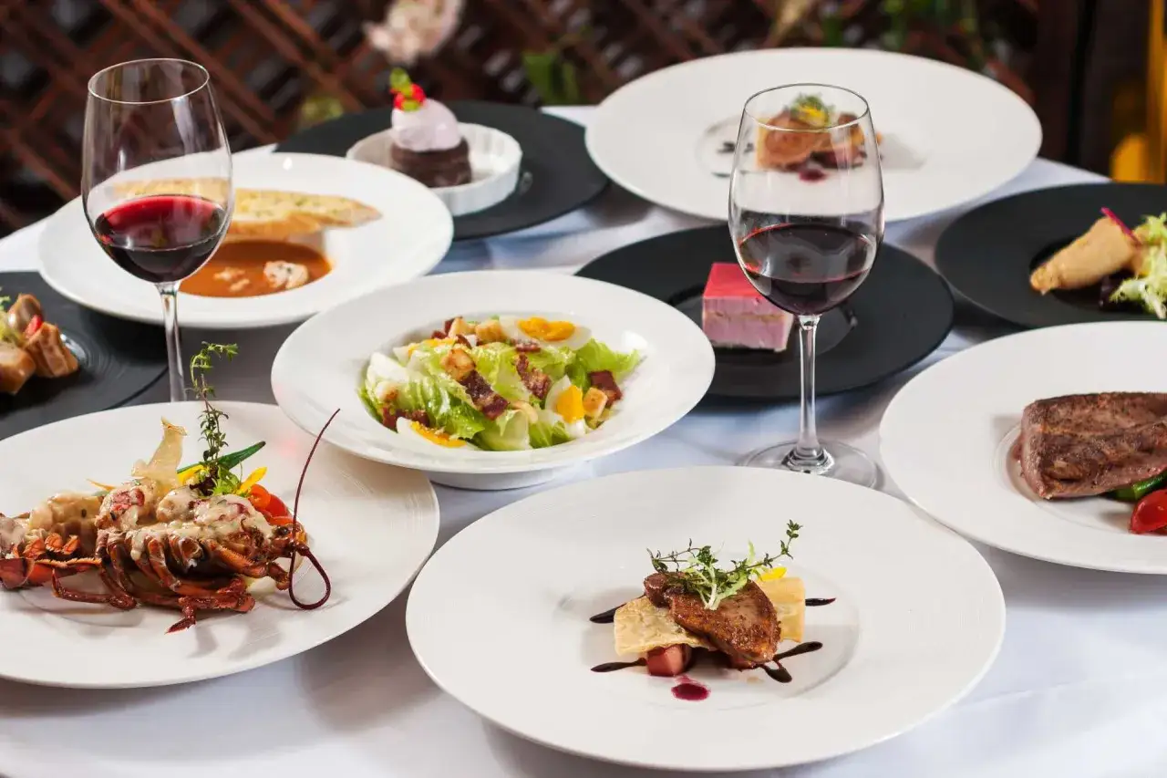 Elegancka kolacja w stylu kuchni francuskiej: homar, steki, sałatka Cezar, desery i czerwone wino.