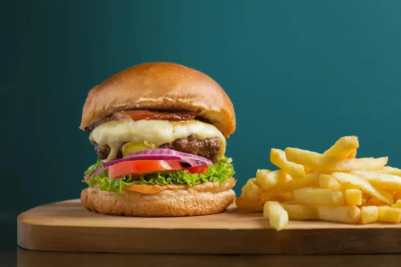 Soczysty burger z serem, warzywami i frytkami. Czy czym się różni hamburger od burgera? To pytanie, na które odpowiedź znajdziesz, próbując tego pysznego dania.