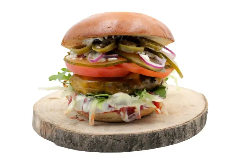 Pikantny jalapeno burger z pomidorem, cebulą i sałatą na drewnianym krążku. Zastanawiasz się nad jego kcal?