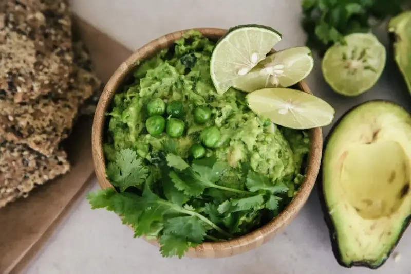 Pyszne guacamole co to? Kremowy dip z awokado, groszkiem, kolendrą i limonką, podany z chrupkimi krakersami.