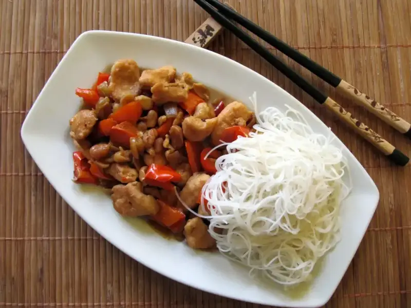 Kurczak kung pao po seczuańsku z orzeszkami ziemnymi i papryką, podany z ryżowym makaronem.